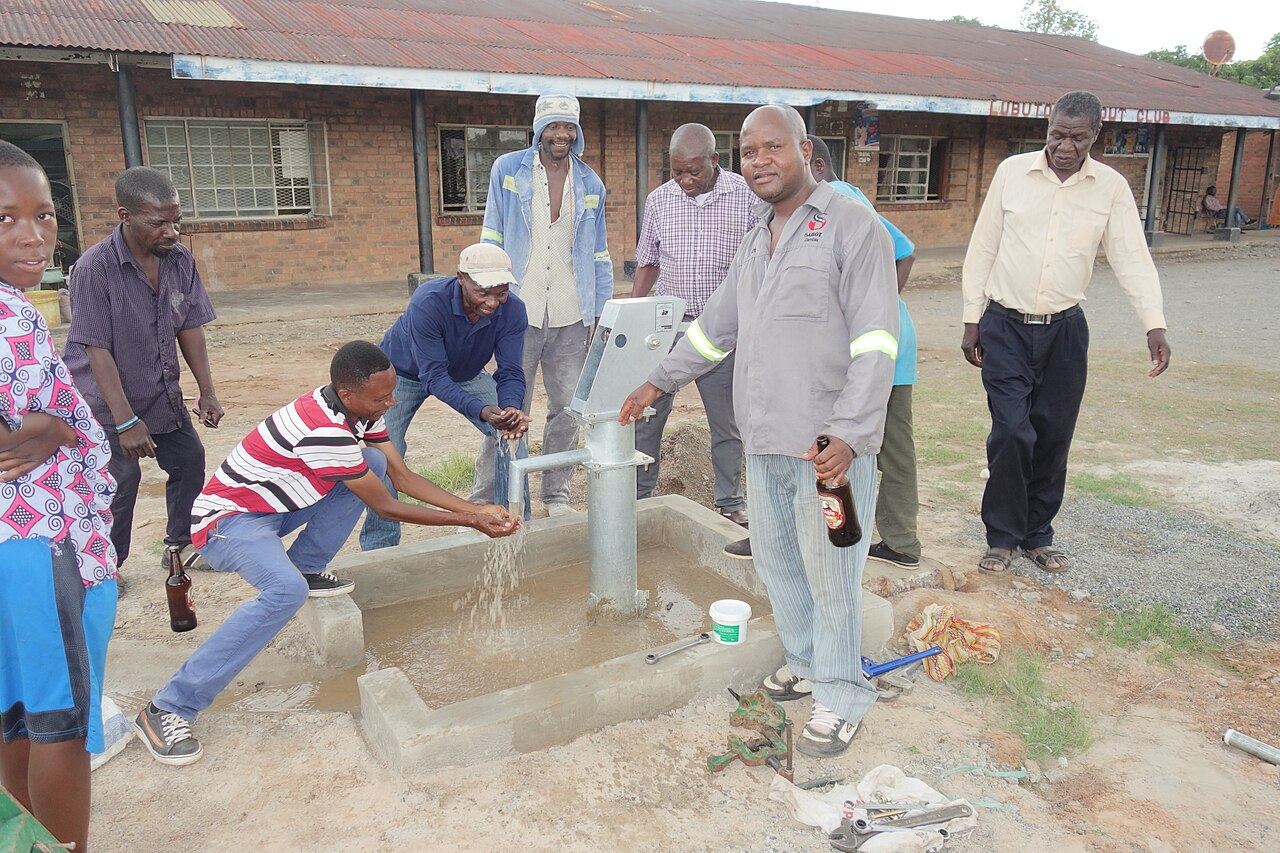 Comunidad usando agua de un pozo recién instalado con bomba manual